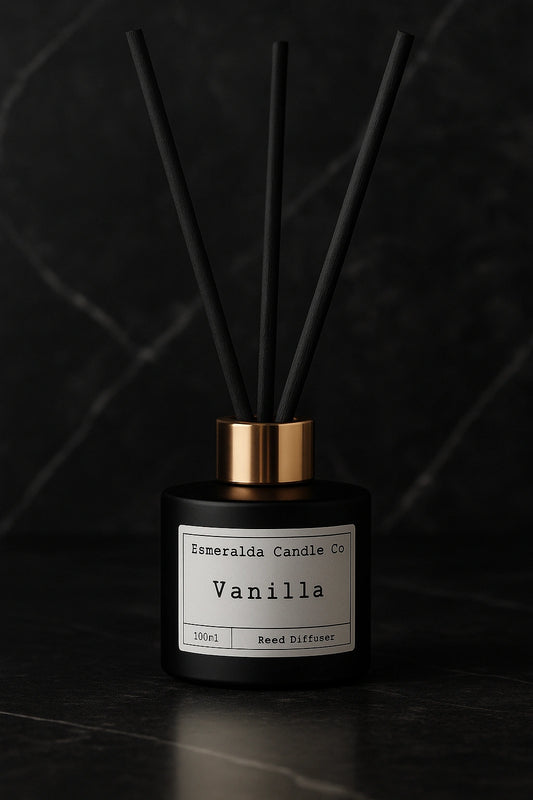Esmeralda Candle Co Vanilla reed diffuser in a matte black bottle with gold collar and black reeds, displayed on a dark marble surface with elegant luxury styling.