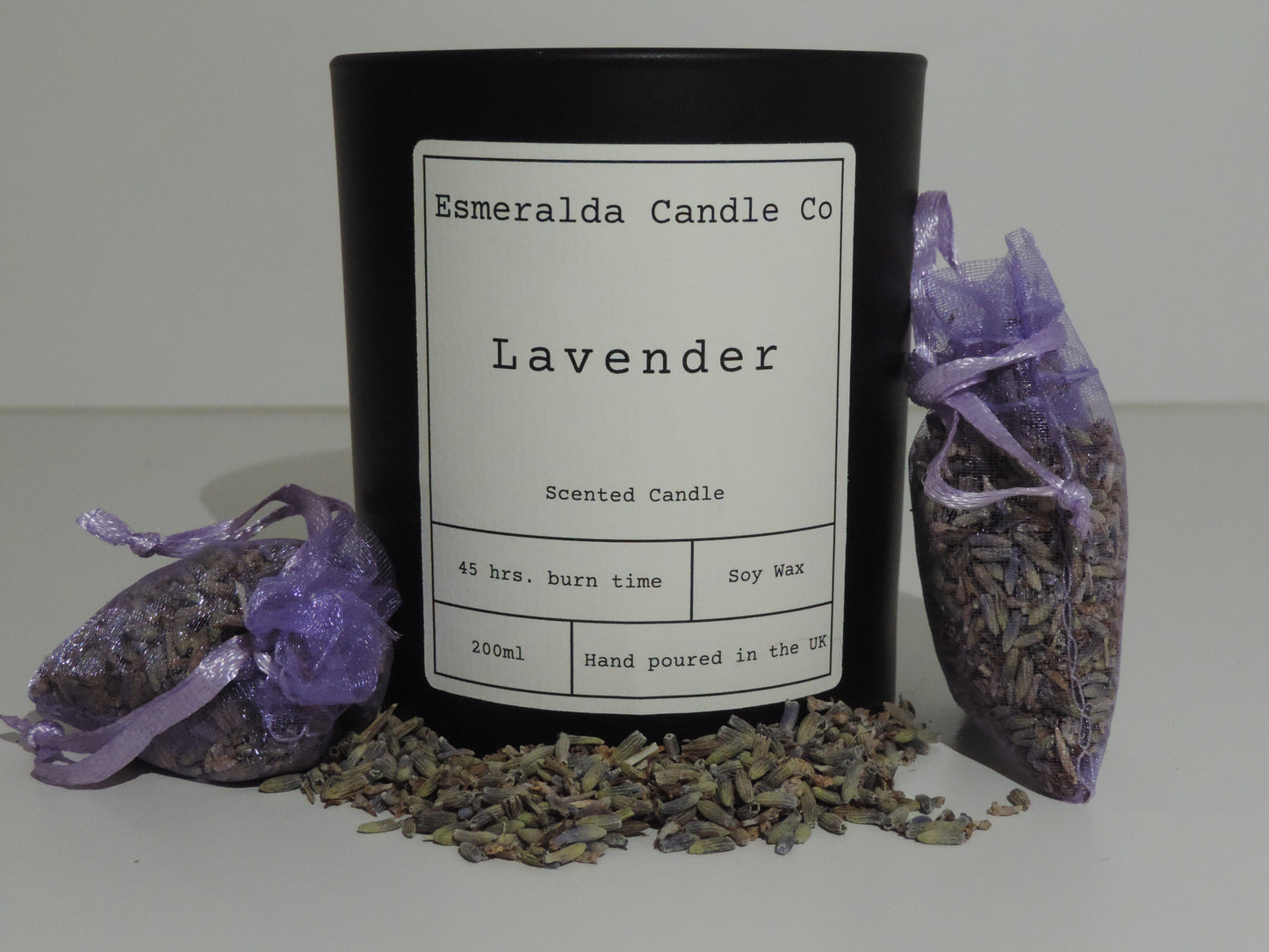 A scented candle with bags of lavender around and loose lavender