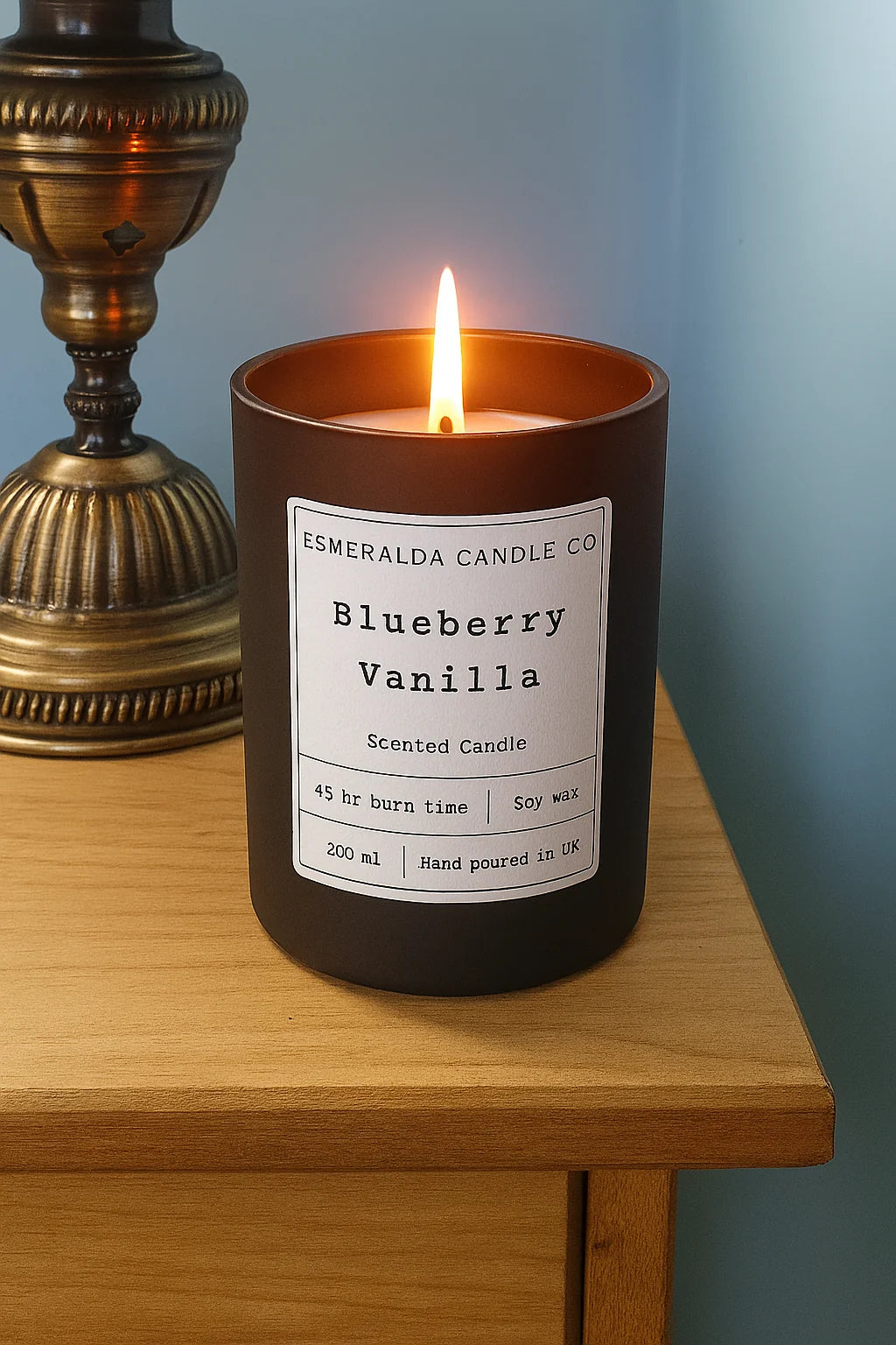 Esmeralda Candle Co. Blueberry Vanilla scented soy wax candle lit on a wooden nightstand beside a colourful mosaic lamp. Hand-poured in the UK with a 45-hour burn time, 200ml jar