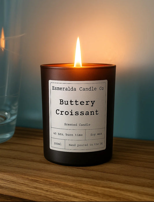Black candle with a label reading 'Esmeralda Candle Co Lime Basil & Mandarin' on a wooden surface.
