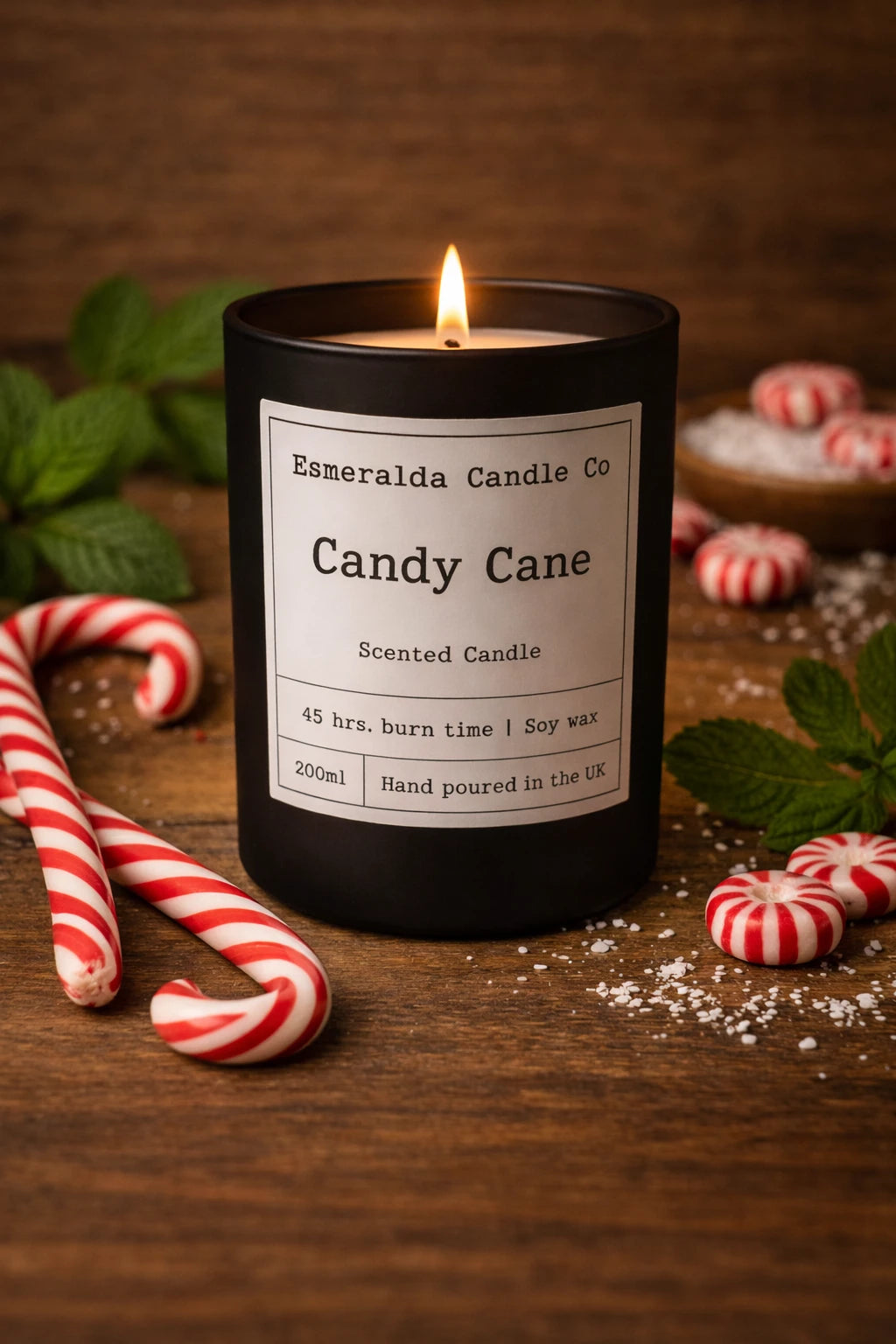 Candle labeled 'Candy Cane' from Esmeralda Candle Co. on a wooden surface with candy canes and peppermints.