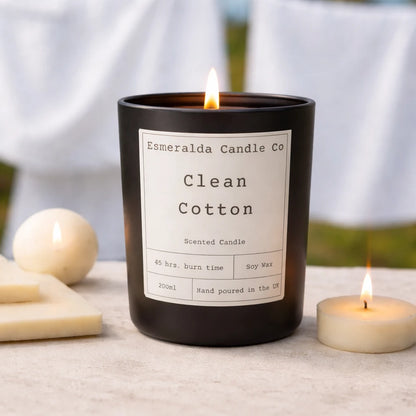 Black candle labeled 'Esmeralda Candle Co Clean Cotton' with a white label on a light surface.
