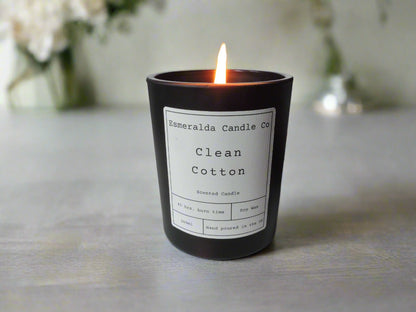 Clean Cotton scented soy wax candle by Esmeralda Candle Co, hand poured in the UK, lit and displayed on a light surface with a soft floral background for a fresh, airy ambiance.