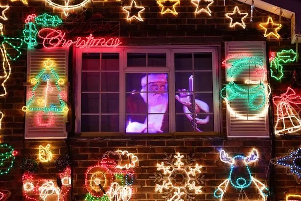Decorative Christmas lights on a window with a person inside, surrounded by festive decorations.