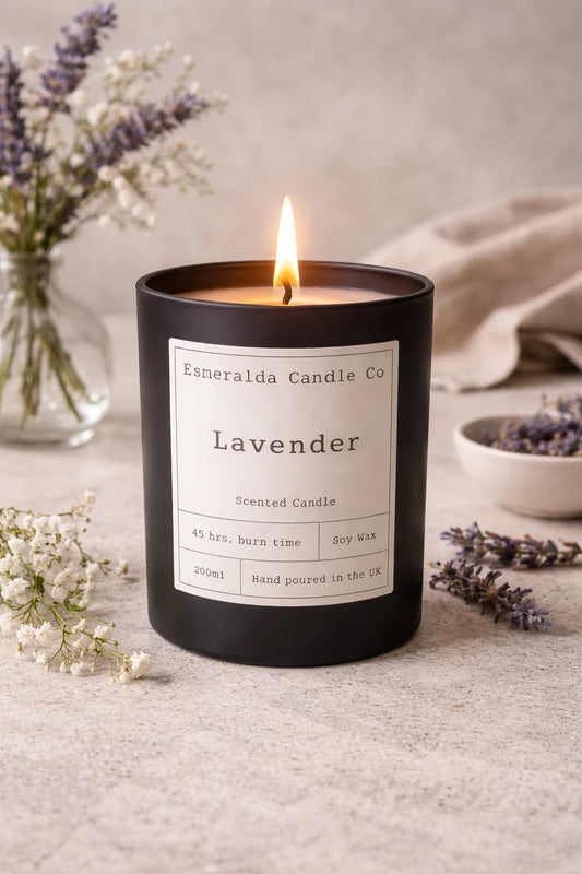 Lavender candle with a label on a textured surface with flowers and a bowl.
