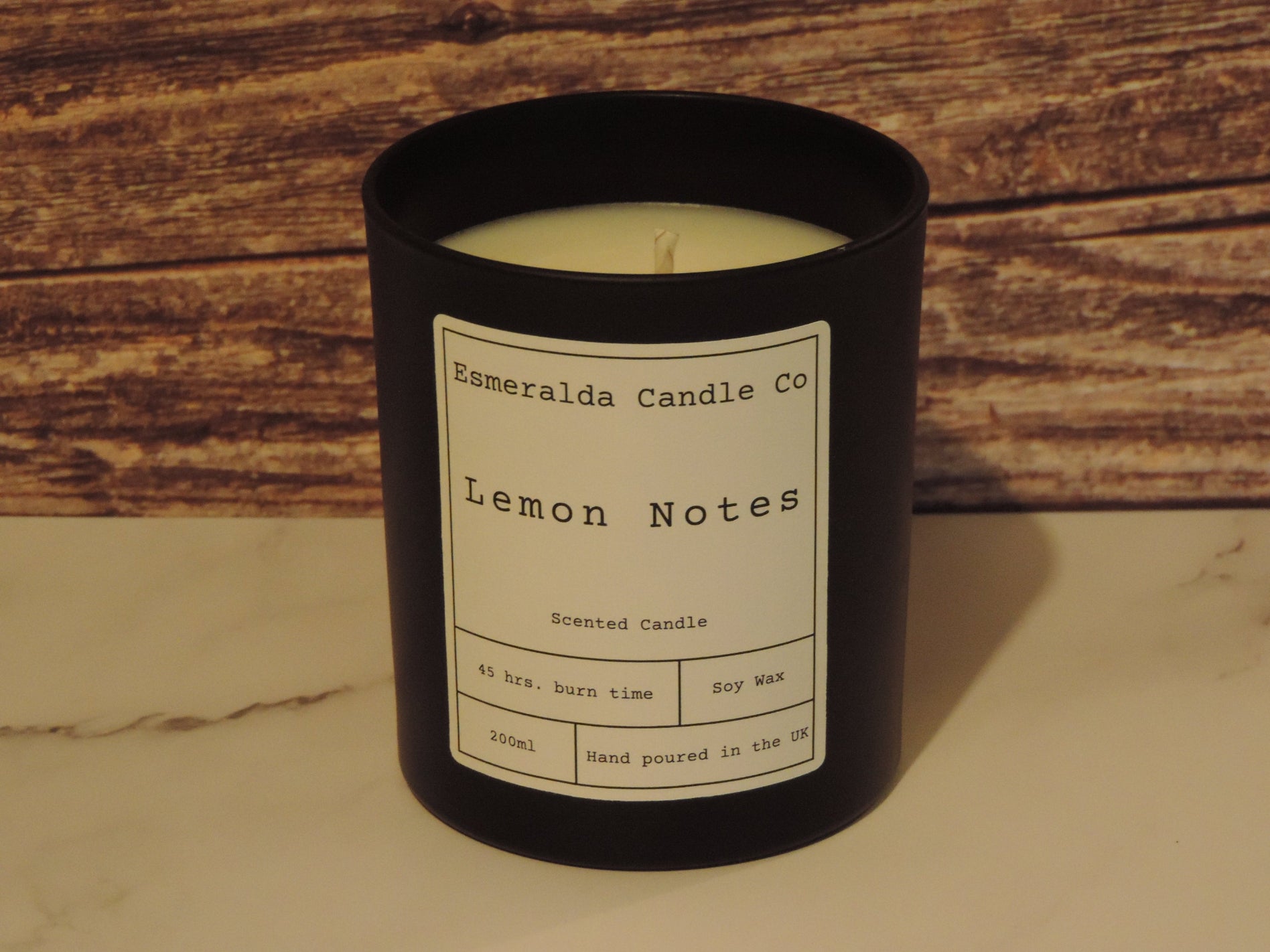 a lemon notes scented candle on a wood and marble shelf