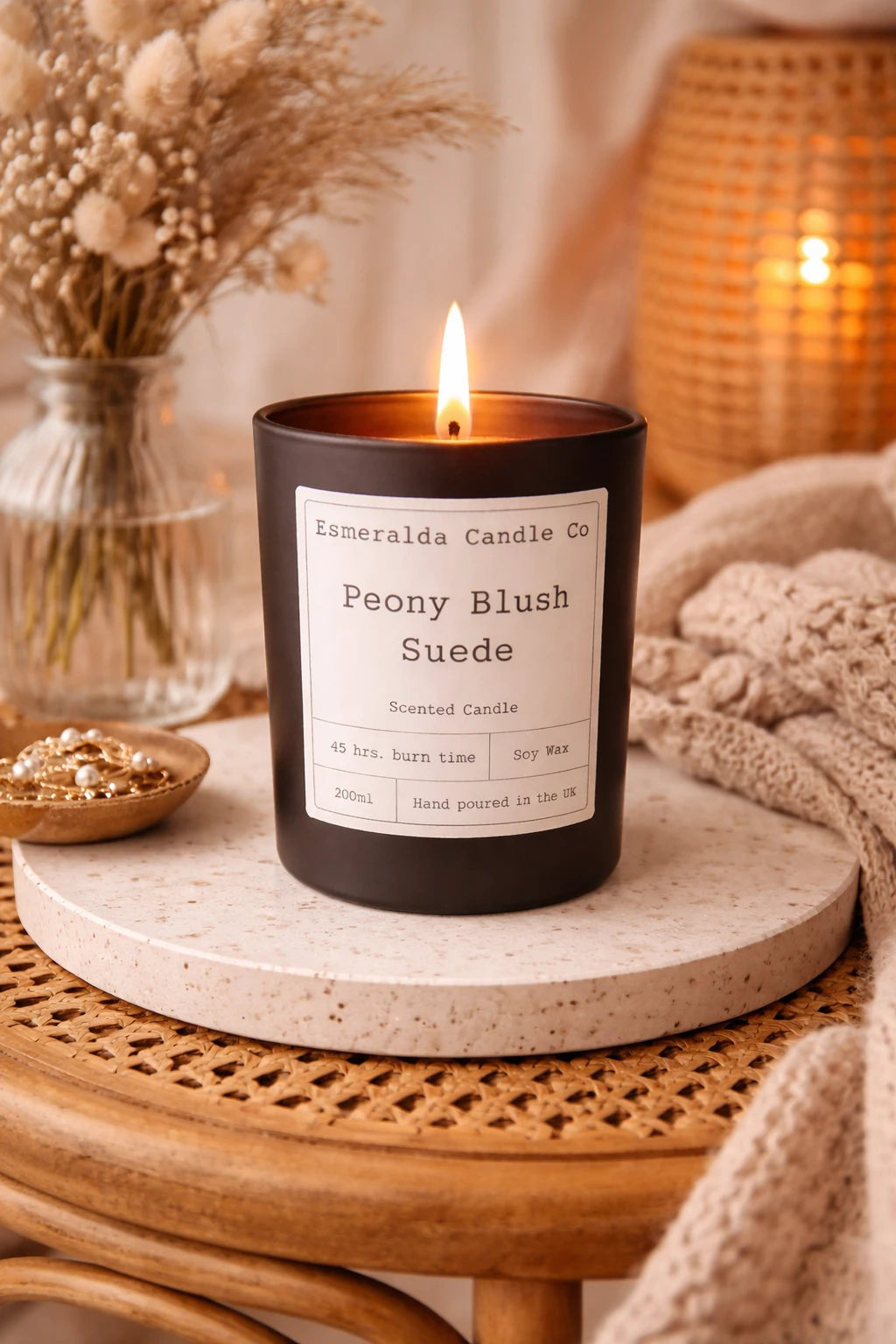 Candle labeled 'Peony Blush Suede' from Limerelda Candle Co on a wooden table with decorative elements.