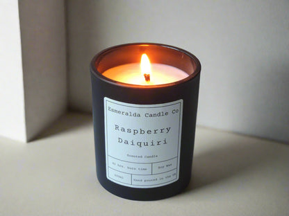 Raspberry Daiquiri scented candle by Esmeralda Candle Co, 200ml soy wax in a matte black jar with 45-hour burn time, hand poured in the UK, lit and styled in a soft neutral setting.
