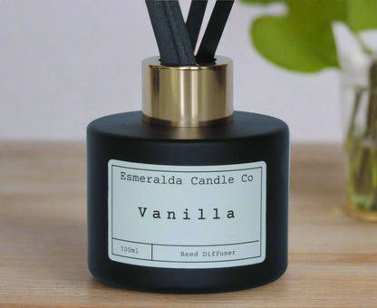 Vanilla reed diffuser by Esmeralda Candle Co, 100ml matte black bottle with gold collar and black reeds, warm and comforting home fragrance.
