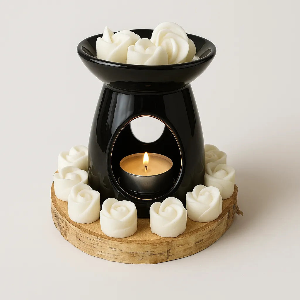 Black ceramic oil burner with a lit tealight candle, surrounded by white rose-shaped wax melts on a wooden base